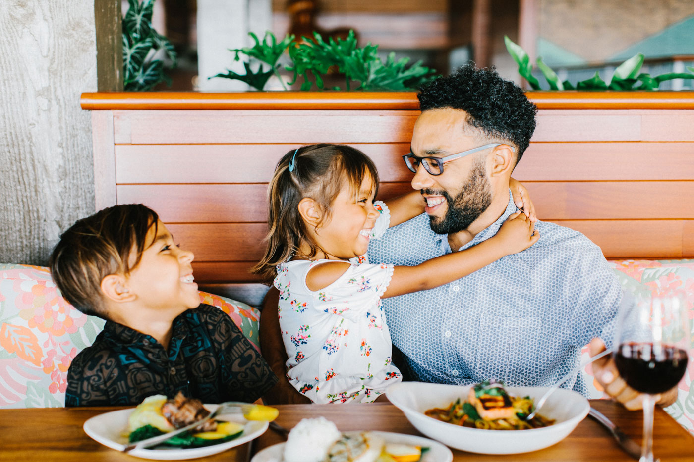 Two kids with their dad eating dinner and drinking wine